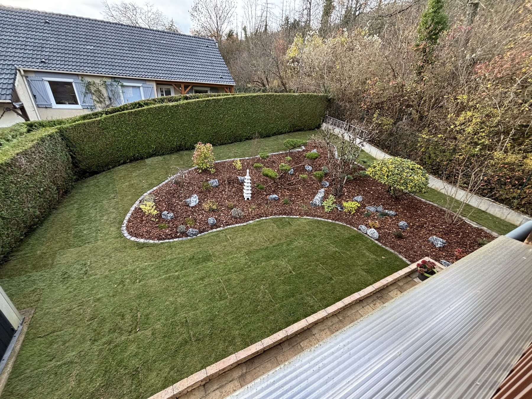 Jardin vu d'en haut : massif en courbe avec rochers et lanterne, gazon et haie taillée